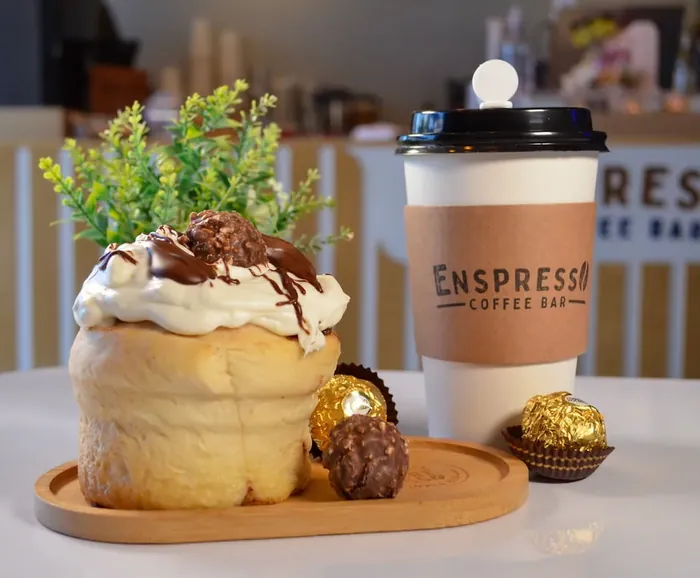 Rol con crema, chocolate y bombones junto a un café caliente
